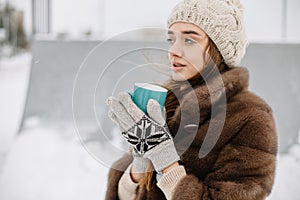 Woman Drinks Hot Tea or Coffee From a Cozy Cup on Snowy Winter Morning Outdoors. Beautiful Girl Enjoying Winter in a Garden with a