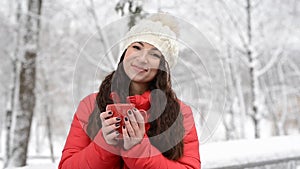 Woman Drinks Hot Tea or Coffee From Cup at Cozy Snowy House Garden on Winter Morning. Beautiful Girl Enjoying Winter Outdoors with