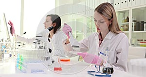 Woman drips liquid onto tray with multiple pipette in lab