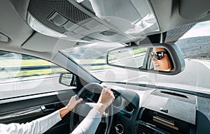 Woman drive a car reflects in back view mirror