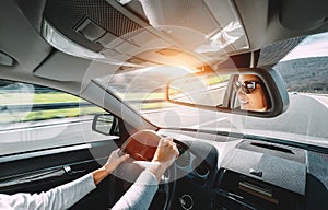 Woman drive a car reflects in back view mirror