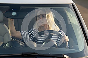 Woman driver beginner worried of problem with parking look in back view mirror afraid of car crash