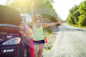 Woman driver with a child on a country road, near a broken car.