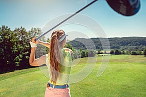 Woman with driver on golf course at the tee photo