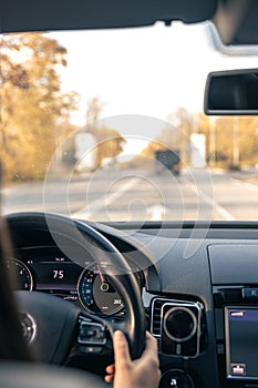 Woman driver hands on steering wheel inside car.