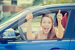 Woman driver happy smiling showing thumbs up sitting inside new car