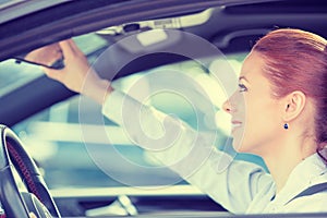Woman driver looking adjusting rear view car mirror