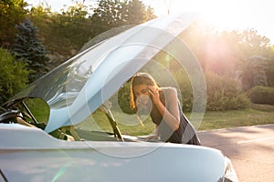 woman driver near broken car with popped hood having a breakdown problem