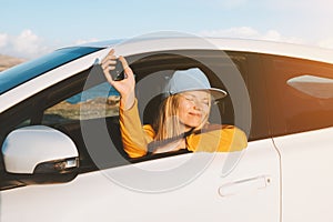 Woman driver in a new car showing keys in open window. Girl buying auto. Road trip travel vacations