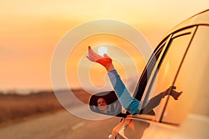 Woman driver putting hand out of car window while driving