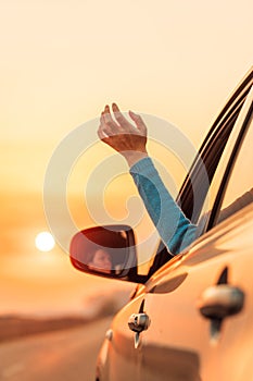 Woman driver putting hand out of car window while driving