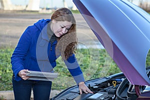 Woman a driver with touchpad repairing broken car