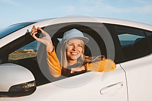 Woman driver traveling in a car showing keys open window. Road trip with rental automobile vacations