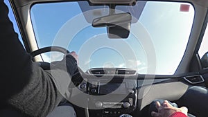 Woman driving a car along the highway, the sun shines in the windshield. low angle view
