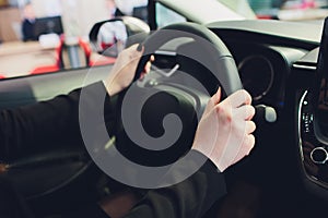 Woman driving a car, hands on steering wheel close-up.