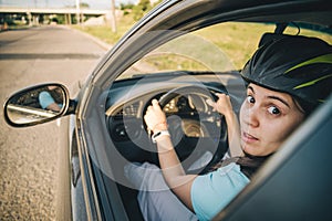 Woman driving car in helmet with horror on her face