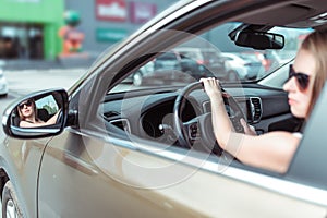 Woman driving a car, looks at side rear-view mirror, reversing, parking shopping center, driving car into garage. In