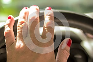 Woman driving a car with one hand holding the steering wheel