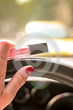 Woman driving a car with one hand holding the steering wheel and tube of lipstick