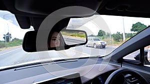 Woman driving car reflects in rear view mirror