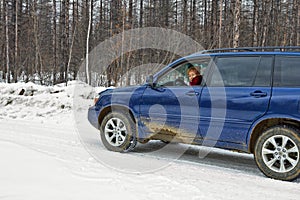 Woman driving a car rides along winter road