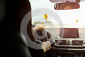 Woman driving car with sign of sharp curves ahead on the road.