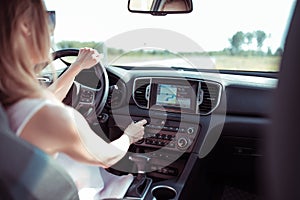 Woman driving car, summer outside city, increases volume on radio, touch screen, automatic transmission, radio station