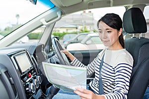 Woman driving car and using map