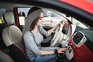 Woman driving new and modern car and turn button on dashboard panel in car