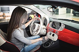 Woman driving new and modern car and turn button on dashboard panel in car