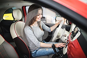 Woman driving new and modern car and turn button on dashboard panel in car