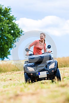 Woman driving off-road with quad bike