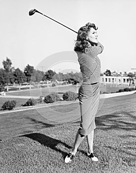 Woman on the driving range swinging a golf club photo