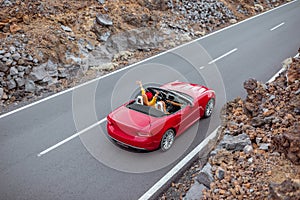 Woman driving red cabriolet on the volcanic valley