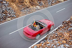 Woman driving red cabriolet on the volcanic valley