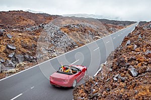 Woman driving red cabriolet on the volcanic valley