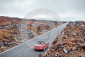 Woman driving red cabriolet on the volcanic valley