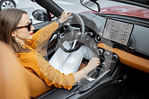 Woman driving sports car with a digital touchscreen