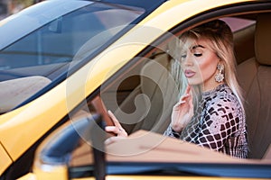 Woman driving yellow sports car with hand hold steering wheel