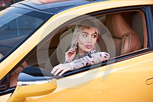 Woman driving yellow sports car with hand hold steering wheel