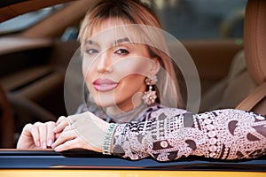 Woman driving yellow sports car with hand hold steering wheel