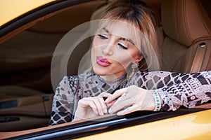 Woman driving yellow sports car with hand hold steering wheel