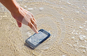 The woman dropped her smartphone into the sea. Lost mobile phone on a sandy beach.