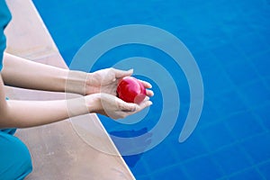 Woman dropping red heart in hands into the water