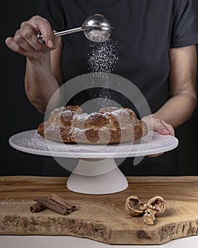 A woman drops icing sugar onto a donut using a duster