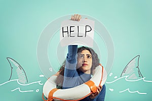 Woman is drowing and ask help with a message of a paper sheet. Cyan background photo