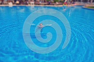 Woman drowns in pool water, tilt shift blurred effect