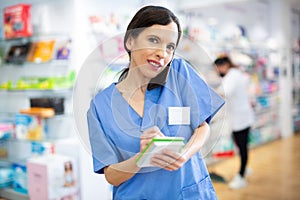 Woman druggist making notes and talking on phone