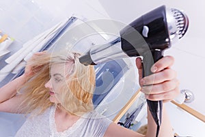 Woman drying hair in bathroom