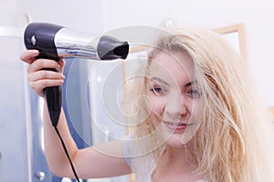 Woman drying hair in bathroom